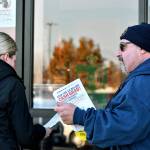 Kevin Flynn, right, a meat-cutter with the Marysville Albertsons, hands a leaflet to a shopper during an informational campaign on Nov. 9, 2022. Flynn was one of about a dozen grocery store workers handing out leaflets to shoppers about the proposed merger between Albertsons and Kroger. (Mike Henneke / The Herald)