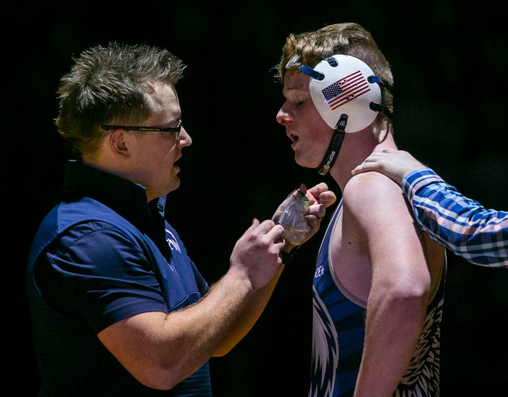Arlington coaches help Holden Strande with nose bleed during the 195 pound weight class match on Tuesday, Jan. 24, 2023 in Arlington, Washington. (Olivia Vanni / The Herald)