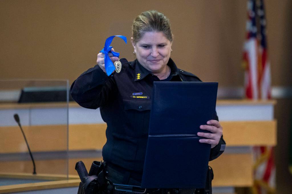 Edmonds Police Chief Michelle Bennett presents K-9 Hobbs and Sgt. Jason Robinson with a medal during Hobbs retirement ceremony at the Edmonds Police Department on Thursday, in Edmonds. (Annie Barker / The Herald)