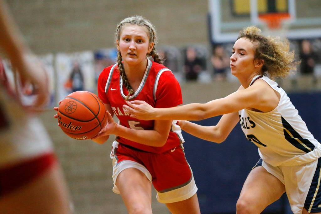 Stanwoods Ava Depew winds up to pass to the paint while being guarded closely against Arlington on Wednesday, Jan. 25, 2023, at Arlington High School in Arlington, Washington. (Ryan Berry / The Herald)