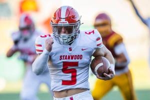 Stanwood’s Ryder Bumgarner breaks away and runs the ball in for a touchdown while his teammates raise their arms and cheer during the 3A quarterfinal game against Odea on Saturday, Nov. 19, 2022 in Seattle, Washington. (Olivia Vanni / The Herald)