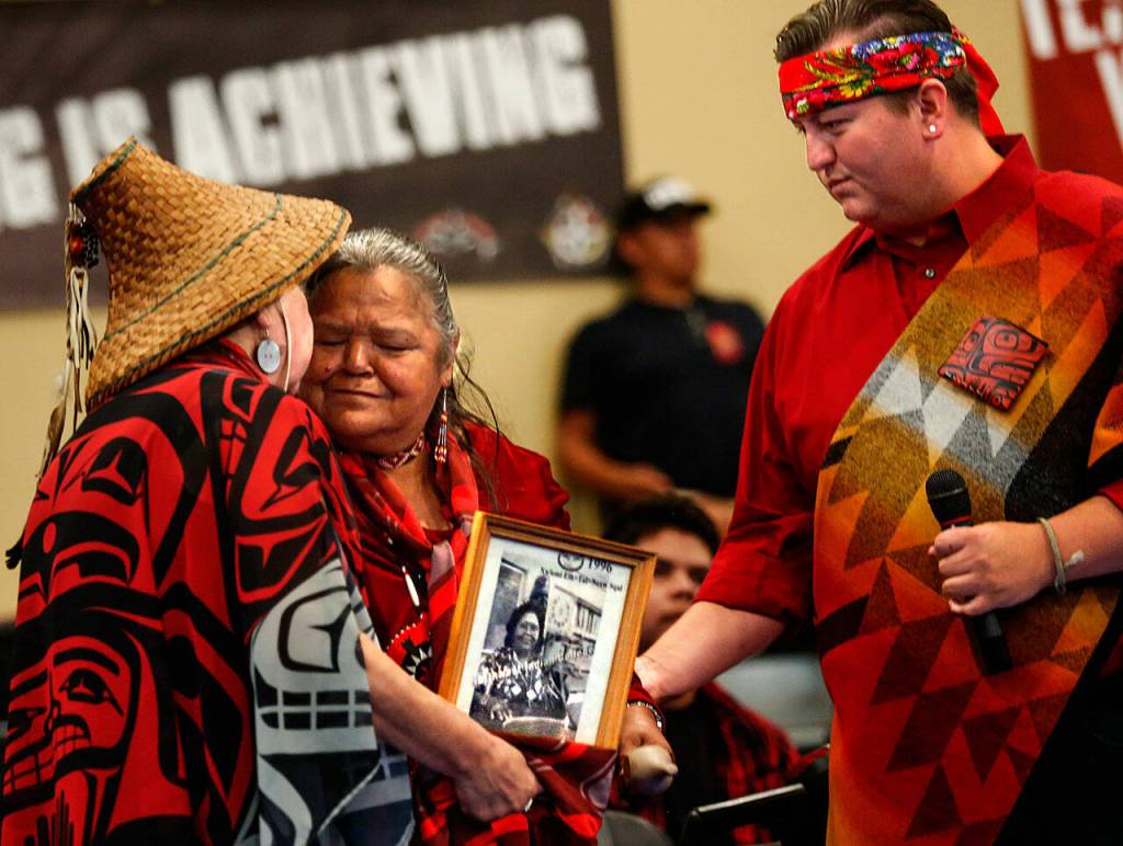 The Tulalip Tribes Karen Fryberg (left) and Andrew Gobin make a presentation to Rita Matta, who speaks on behalf of her mother, Etta Jones. Mattas mother was in the hospital on this day that she was to be honored. Holding a photo of her mother, Matta spoke about her mom working hard all her life, raising 11 children. She worked hard at being a mother, Matta said. (Dan Bates / The Herald)