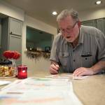 Ron Thompson looks over disaster planning maps of Oso at his home. (Ryan Berry / The Herald)