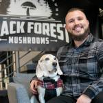 Nathanael Engen, founder of Black Forest Mushrooms, sits in the lobby of Think Tank Cowork with his 9-year-old dog Bruce Wayne on Jan. 27, in downtown Everett. (Ryan Berry / The Herald)