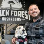 Nathanael Engen, founder of Black Forest Mushrooms, sits in the lobby of Think Tank Cowork with his 9-year-old dog, Bruce Wayne, on Friday, Jan. 27, 2023, in downtown Everett, Washington. (Ryan Berry / The Herald)