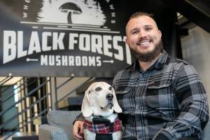 Nathanael Engen, founder of Black Forest Mushrooms, sits in the lobby of Think Tank Cowork with his 9-year-old dog, Bruce Wayne, on Friday, Jan. 27, 2023, in downtown Everett, Washington. (Ryan Berry / The Herald)