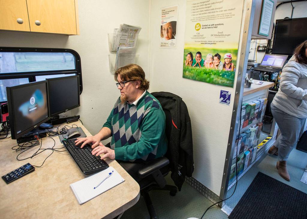 Public benefits specialist Ryann Langlois logs into his computer before the DSHS Mobile Office opens on Tuesday, in Gold Bar. (Olivia Vanni / The Herald)