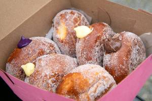 Lori Johnson, director of the Washington State Food Truck Association shows off a box of fresh malasadas during the grand opening of the GoodBelly LLC food truck on Saturday, Jan. 28, 2023, in Everett, Washington. (Ryan Berry / The Herald)