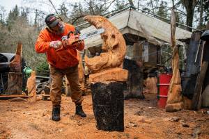 Steve Backus works on the details of a moon carving at his wood shop and home on Monday, Feb. 6, 2023 in Clinton, Washington. (Olivia Vanni / The Herald)