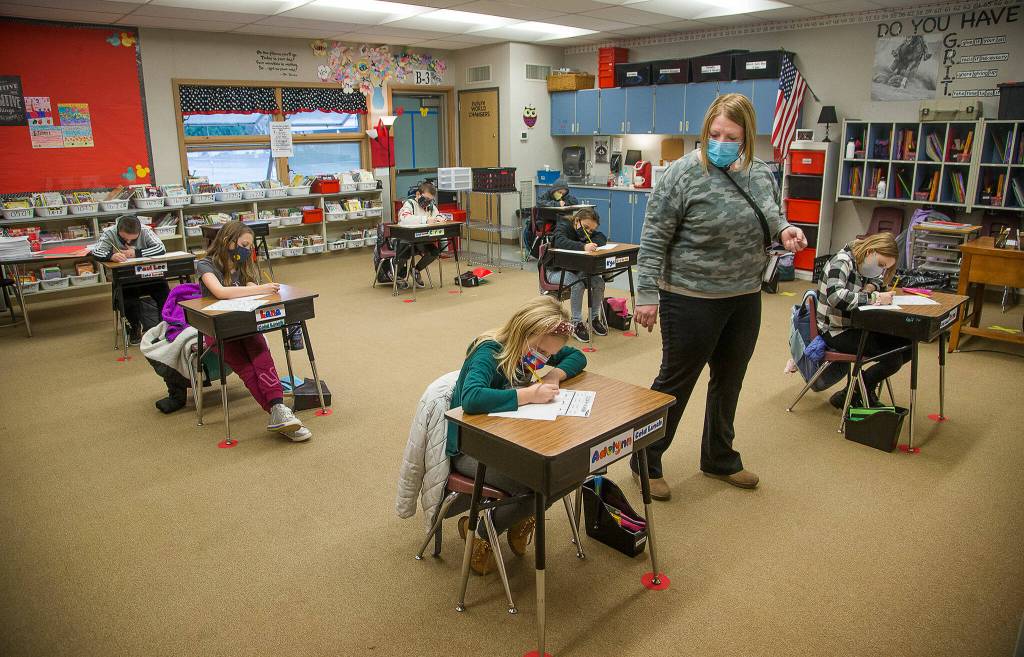 Third grade teacher Lisa Thompson walks by her ten students, separated at six-foot distance, at Eagle Creek Elementary on Jan. 27, 2021 in Arlington. (Andy Bronson / The Herald)