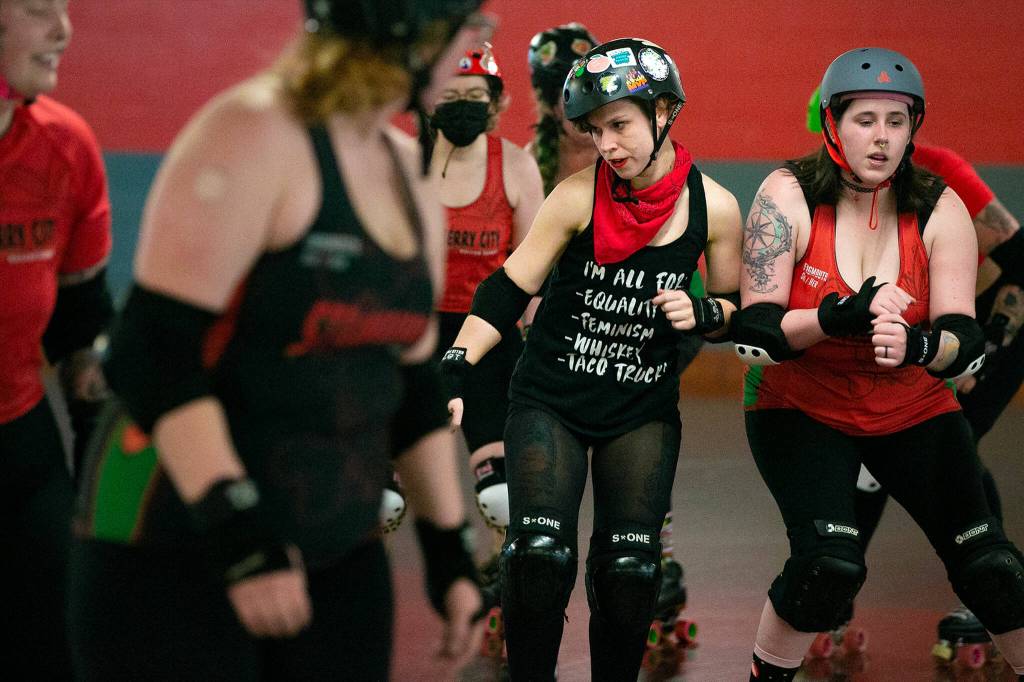 Hannibal Lecture Hannah Jones, center, bumps into Rina Rock You Marina Kolbeck while practicing weaving and checking with teammates in a pace line during a Strawberry City Roller Derby practice at Marysville Skate Center on Monday, Feb. 6, in Marysville. (Ryan Berry / The Herald)