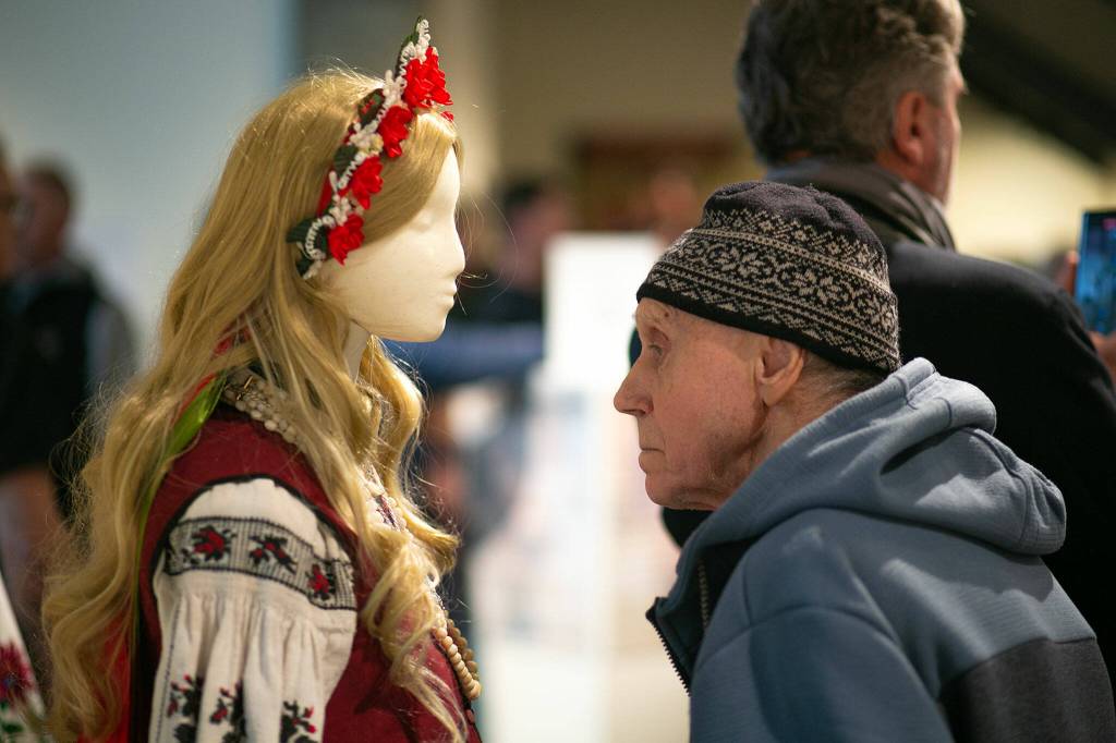A man takes a long pause to look at the detail of some traditional bridal attire on display during a public event highlighting the For Ukraine: Art of Freedom exhibit at the Schack Art Center on Saturday, in downtown Everett. (Ryan Berry / The Herald)