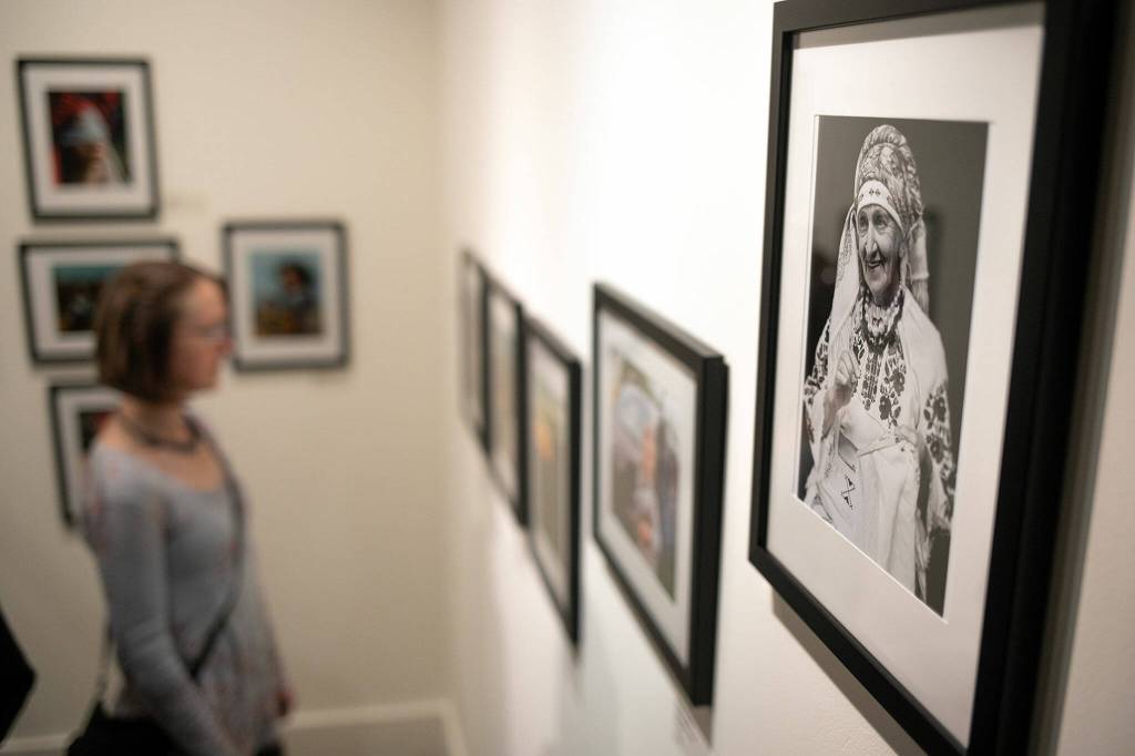 A woman peruses a corner of photographic prints by multiple Ukrainian artists during a public event highlighting the For Ukraine: Art of Freedom exhibit at the Schack Art Center on Saturday, in downtown Everett. (Ryan Berry / The Herald)
