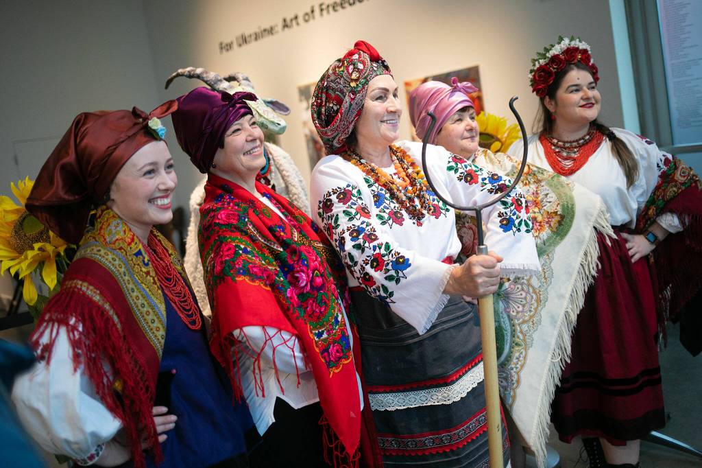 Members of the Ukrainian Association of Washington State take photos with guests during a public event highlighting the For Ukraine: Art of Freedom exhibit at the Schack Art Center on Saturday, in downtown Everett. (Ryan Berry / The Herald)