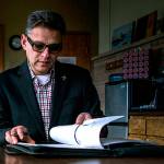 Arif Ghouseat flips through his work binder in his office conference room Paine Field on Monday, Dec. 10, 2018 in Everett, Wa. (Olivia Vanni / The Herald)