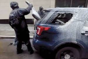 A suspect removes a rifle bag from a broken rear window of a Seattle police car on May 30 in downtown Seattle. An Everett man, Jacob D. Little, 24, has been charged with the theft of the high-powered rifle stolen from the car. This image is from the criminal complaint filed in U.S. District Court. 20200904
