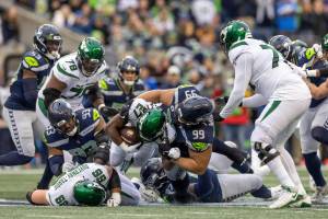 Seattle Seahawks defensive tackle Al Woods (99) tackles New York Jets running back Zonovan Knight (27) in an NFL football game, Sunday, Jan. 1, 2023, in Seattle, Wash. Seahawks won 23-6. (AP Photo/Jeff Lewis)