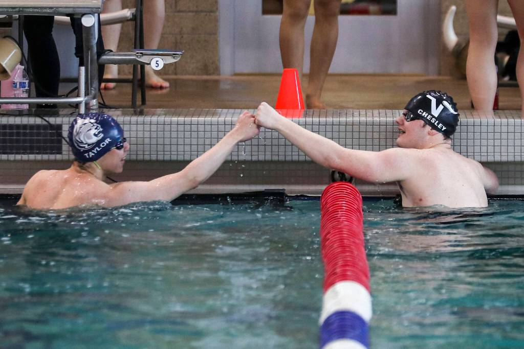 Lake Stevens Garrett Chesley, right, and Glacier Peaks Kaiu Taylor, left, fist-bump after a race during the 4A District 1 swim and dive championships at Snohomish Aquatic Center, in Snohomish, Washington on Saturday, Feb. 11, 2023. (Annie Barker / The Herald)