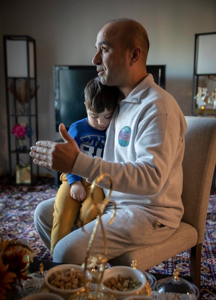 Mohammad Zamir Omar speaks about his familys journey from Afghanistan while his 3-year-old son leeps on his lap at their home on Tuesday, Feb. 14, in Lynnwood. (Olivia Vanni / The Herald)