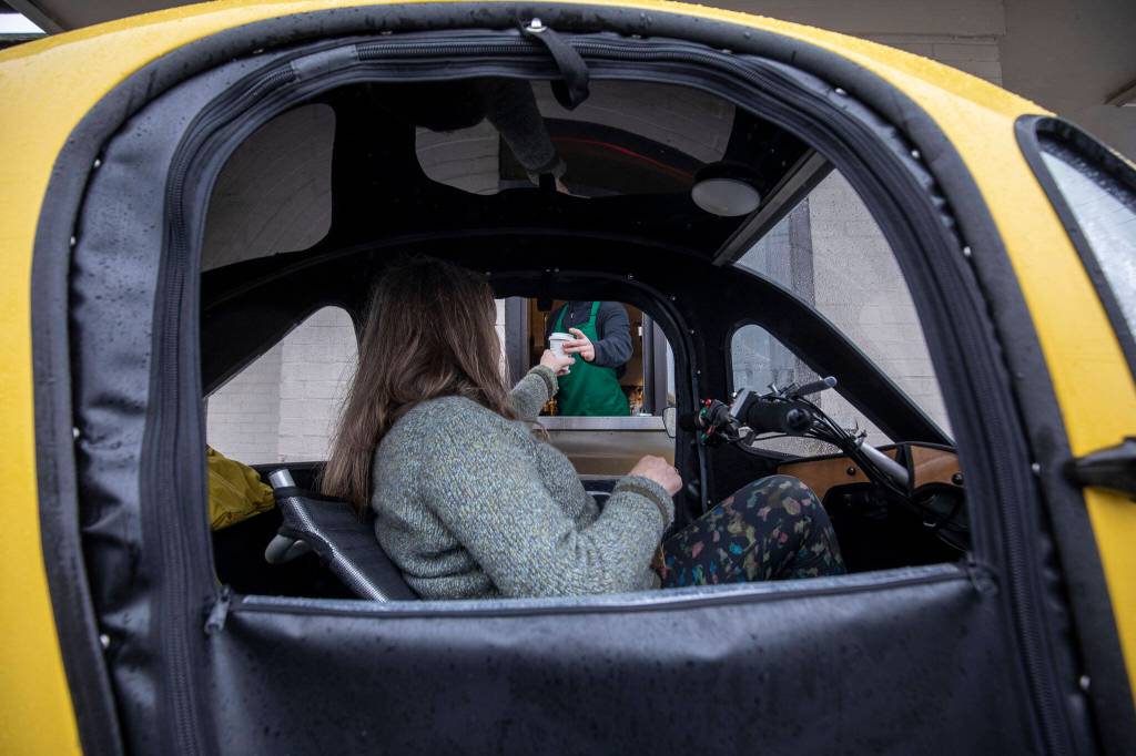 Paula Townsell pedals her PEBL in a Starbucks drive-thru in Everett. (Annie Barker / The Herald)