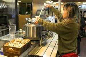 Suzie Zhu serves herself Ivar's clam chowder on the Edmonds-Kingston ferry run. The floating food courts offer a variety of Washington products, including sandwiches, beer, wine and ice cream. Ivar's chowder and chili is $4.50 to $5.75. (Kevin Clark / The Herald)