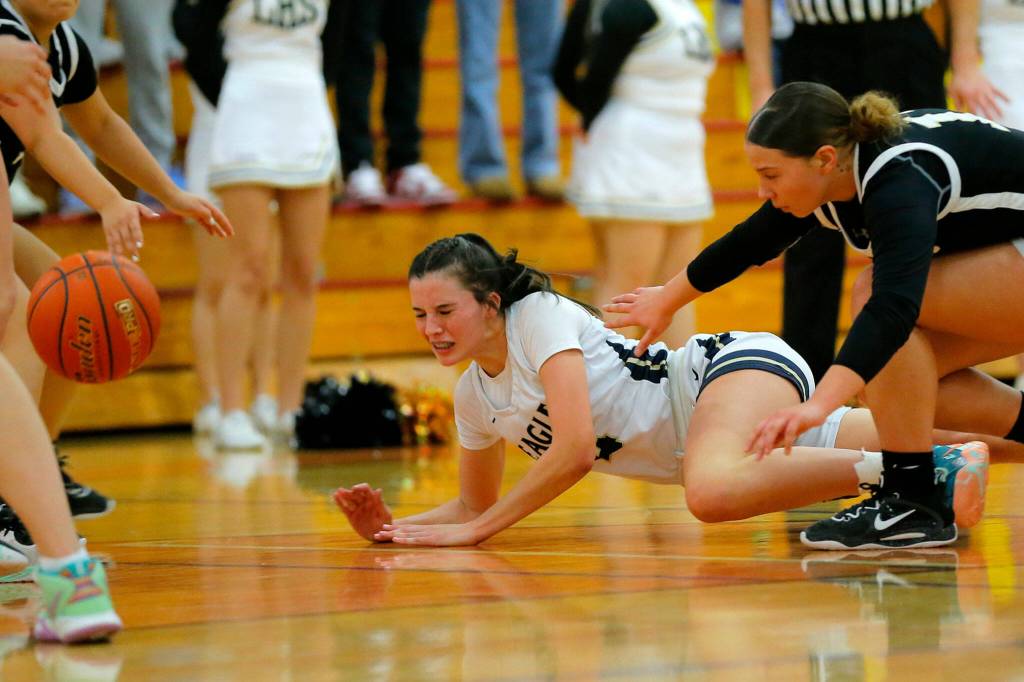 Arlingtons Maddy Fischer hits the deck after getting fouled on a loose ball against Lynnwood on Tuesday, Feb. 14, 2023, at Marysville Pilchuck High School in Marysville, Washington. (Ryan Berry / The Herald)