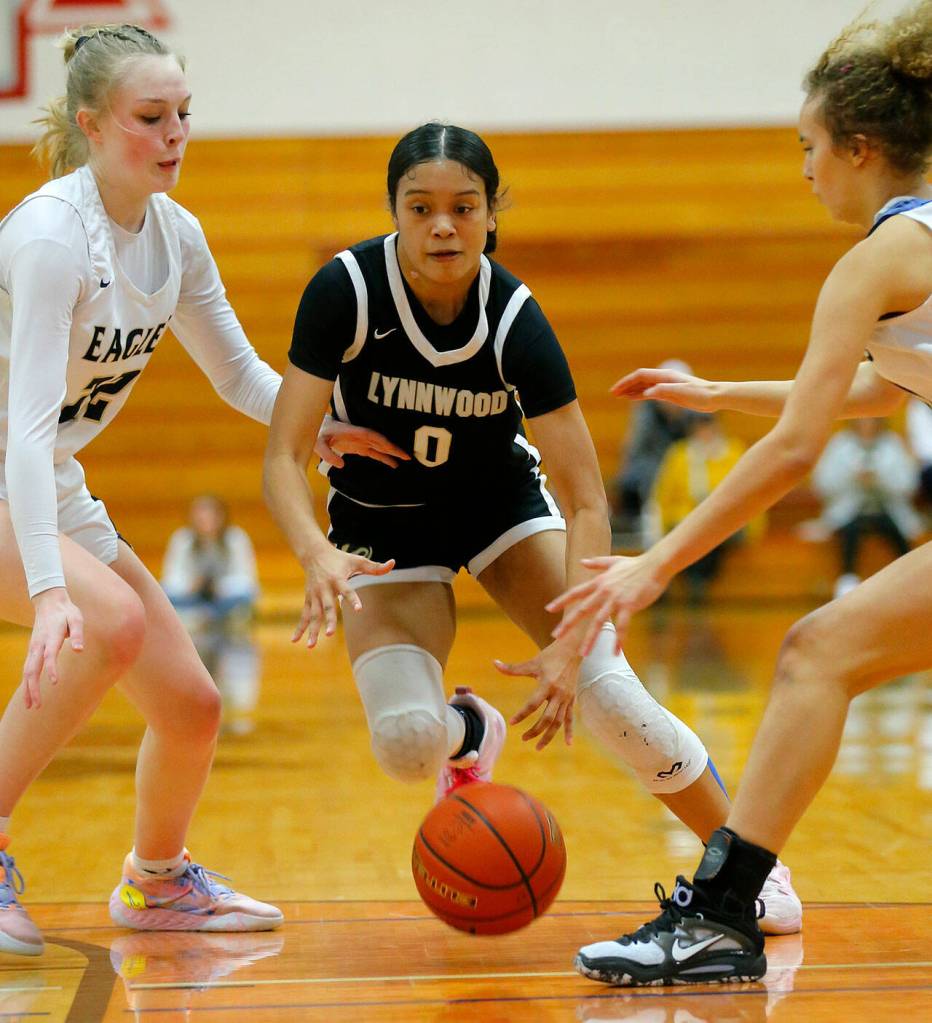 Lynnwoods Aniya Hooker gets pestered by the defense before passing off the ball against Arlington on Tuesday, Feb. 14, 2023, at Marysville Pilchuck High School in Marysville, Washington. (Ryan Berry / The Herald)