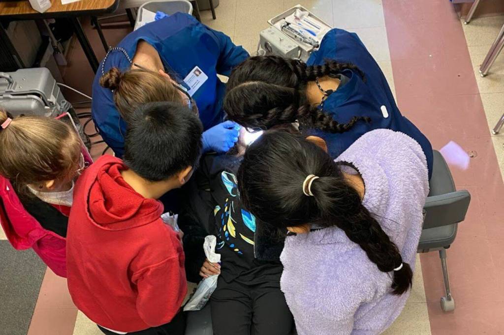 Children at Discovery Elementary School in Everett lean in to see Amanda Good seal molars Feb. 7. (Mukilteo School District)