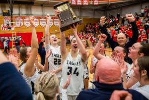 Arlington’s Jenna Villa lifts the 3A District 1 championship trophy in the air on Saturday, Feb. 18, 2023 in Everett, Washington. (Olivia Vanni / The Herald)