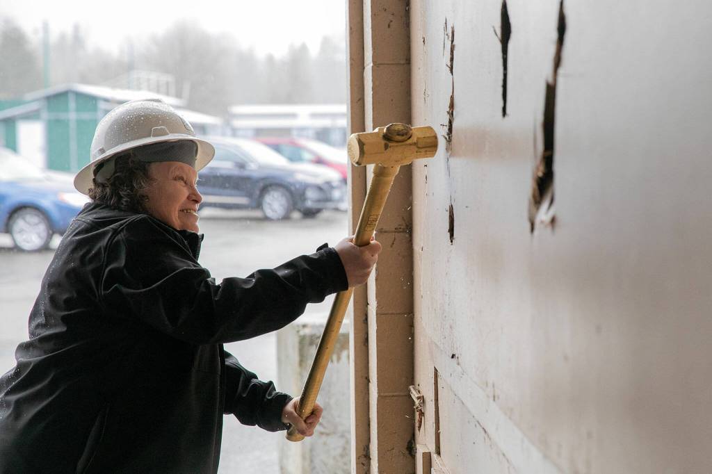 Marshia Armstrong, Chairperson of the Evergreen State Fair Advisory Board, takes a swing at a wall with a golden sledgehammer during an event celebrating the impending demolition of Commercial Building No. 400 Tuesday, at the Evergreen State Fairgrounds in Monroe. (Ryan Berry / The Herald)