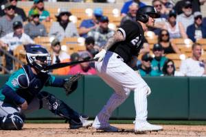 Chicago White Sox's Yasmani Grandal (24) watches the flight of his single as Seattle Mariners catcher Brian O'Keefe looks on during the second inning of a spring training baseball game Monday, Feb. 27, 2023, in Phoenix. (AP Photo/Ross D. Franklin)