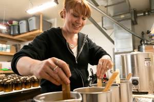 Lacie Marsh-Carroll stirs wax before pouring candles in her garage at her home on March 17, 2018 in Lake Stevens. (Kevin Clark / The Daily Herald)
