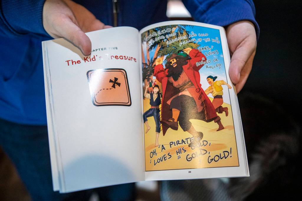 Kelly Matthews, 36, holds open one of her graphic novels on Feb. 2 in her home in Lynnwood. (Annie Barker / The Herald)