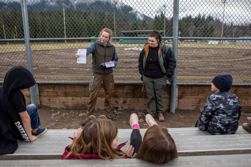 Instructors Hannah Dreesbach, left, and Bailey Huff, right, discuss how to identify trees near Darrington Elementary School on Feb. 17 in Darrington. Environmental and outdoor education lessons are woven throughout the in-school and after-school activities in this small community, thanks to the Glacier Peak Institute. The non-profit arose from community concerns in the wake of the Oso landslide disaster. (Annie Barker / The Herald)