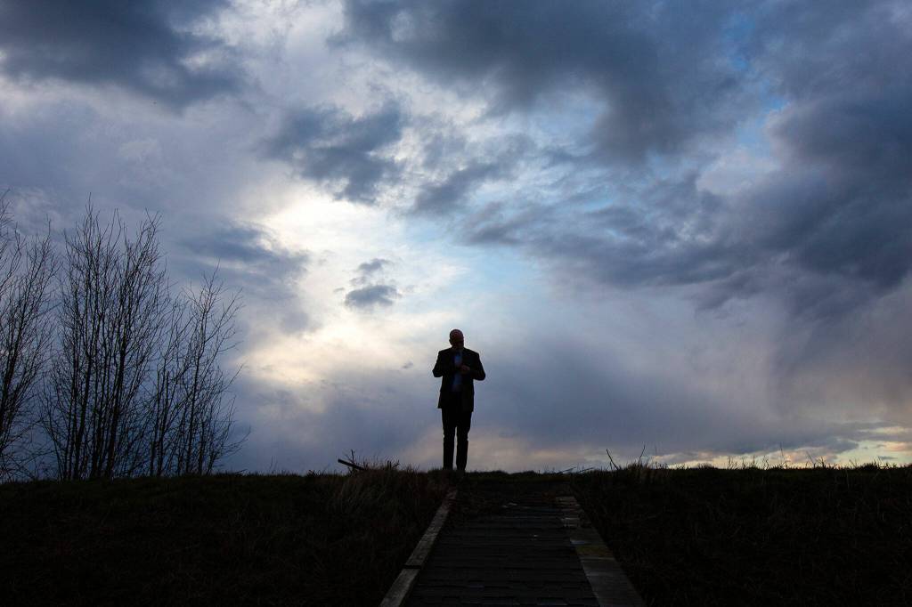 Mayor Sid Roberts stands atop the more-than-100-year-old dike that runs for 4 miles parallel to Skagit Bay on Tuesday, March 7, 2023, on the west end of Stanwood, Washington. The dike failed during Roberts first month as mayor in December 2021, and he and the city have now secured a portion of the $7 million needed to bolster the wall. (Ryan Berry / The Herald)