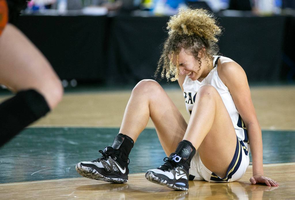 Arlingtons Samara Morrow winces while getting up after hitting the ground hard on a loose ball against Lake Washington in the 3A semifinal on Friday, March 3, 2023, at the Tacoma Dome in Tacoma, Washington. (Ryan Berry / The Herald)