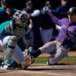Colorado Rockies' Zac Veen (73) scores past Seattle Mariners catcher Cal Raleigh, left, off an RBI-single by Rockies' Brian Serven during the second inning of a spring training baseball game Saturday, March 4, 2023, in Peoria, Ariz. (AP Photo/Abbie Parr)