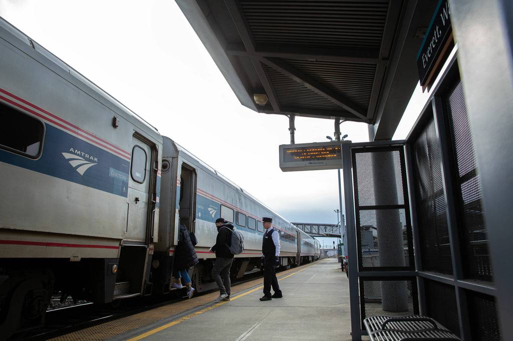 A conductor follows two final passengers onto Amtrak Cascades train 517 from Vancouver to Portland during a stop at Everett Station. (Ryan Berry / The Herald)