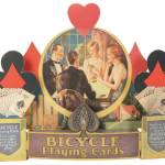 When advertisements include pictures of people, their clothing and hairstyles can help date the item. This store display for Bicycle Playing Cards is from about 1930.