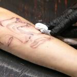 Hurtado wipes down Cheyenne Stultzs arm. Fine line artists such as Hurtado use single needles to create softer, more intricate-looking portraits. (Ryan Berry / The Herald)