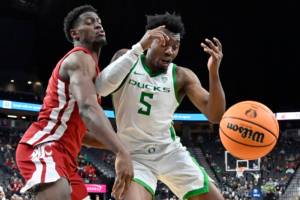 Washington State guard TJ Bamba, center and Oregon guard Jermaine Couisnard (5) chase the ball during the second half of an NCAA college basketball game in the quarterfinals of the Pac-12 Tournament, Thursday, March 9, 2023, in Las Vegas. (AP Photo/David Becker)