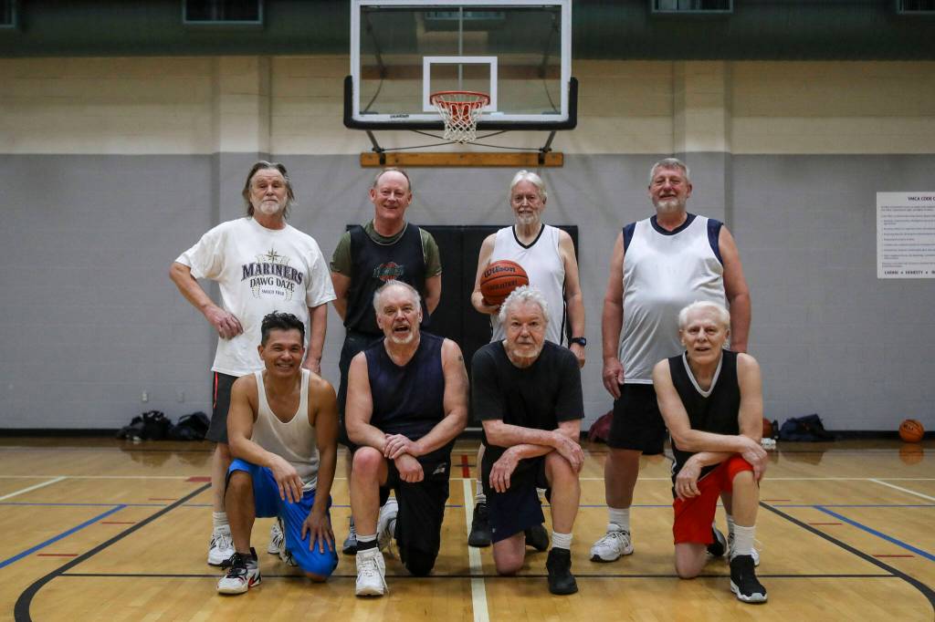 Back row followed by front row left to right, Mac Sheridan, 70, John White, 66, Richard Smith, 74, Jim Dodge, 67, Nome McCaffrey, 57, Steve Powell, 66, Bill Roy, 76, and Sal Fonceca, 74, pose for a photo after one of their regular pick-up game of basketball at the Marysville YMCA in Marysville, Washington on Monday, March 13, 2023. (Annie Barker / The Herald)