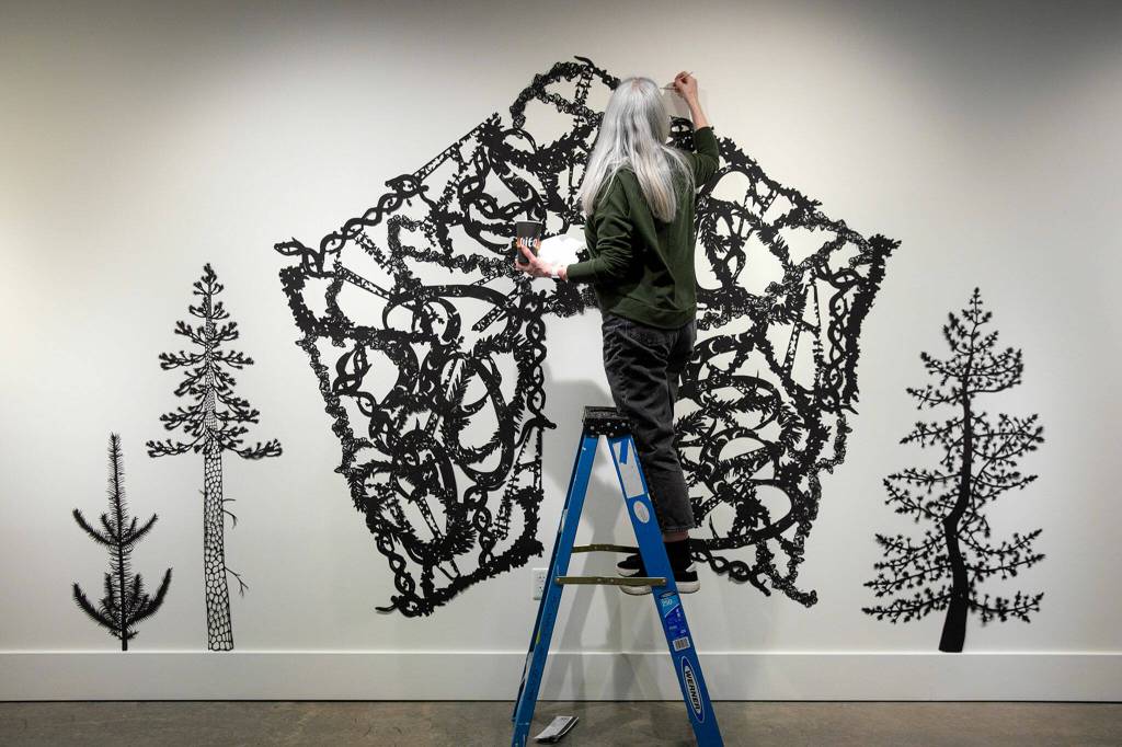 Artist Ann Chadwick Reid puts the finishing touches on a delicate piece called Solastalgia during the setup for Exploring The Edge at Schack Art Center on Sunday, March 19, 2023, in Everett, Washington. (Ryan Berry / The Herald)