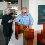 Steve Klein moves some of his glasswork into place as fellow guest curator Meg Holgate watches during installation of A Precarious Edge at Schack Art Center on Sunday, March 19, 2023, in Everett, Washington. (Ryan Berry / The Herald)
