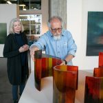 Steve Klein moves some of his glasswork into place as fellow guest curator Meg Holgate watches during installation of A Precarious Edge at Schack Art Center on Sunday, March 19, 2023, in Everett, Washington. (Ryan Berry / The Herald)