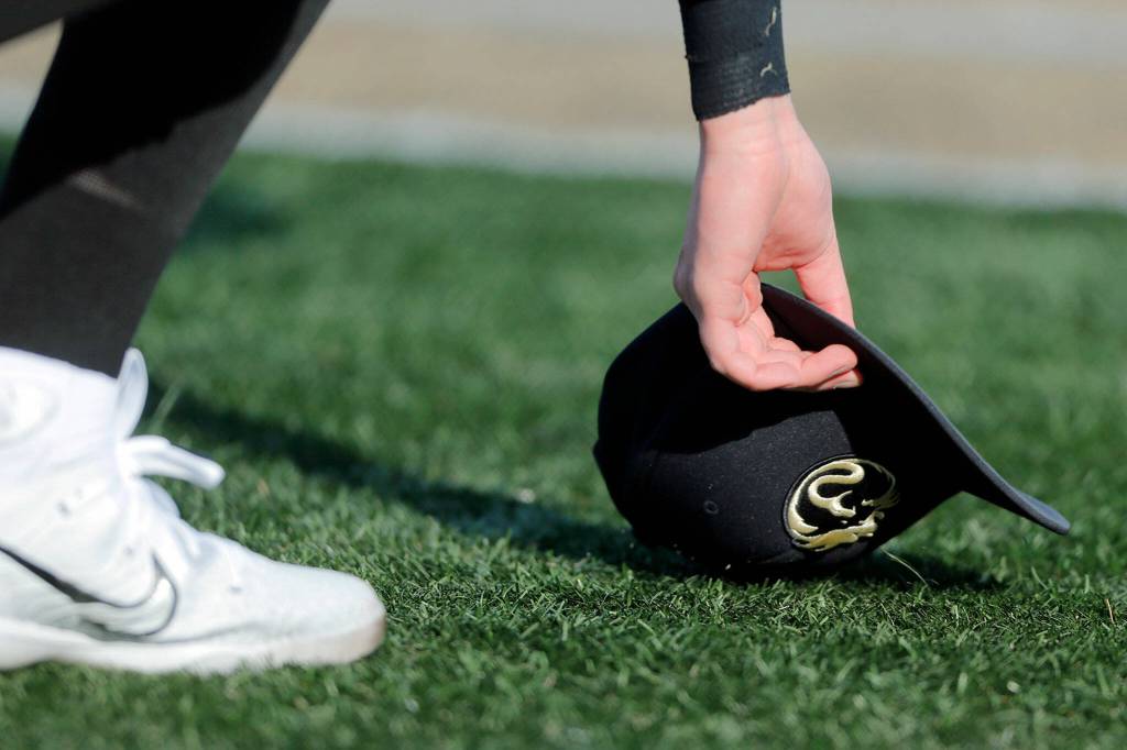 Lynnwood’s Gavin Harrington picks up his cap after losing it on a play in foul territory during a game against Lake Stevens on Friday, March 17, 2023, at Lake Stevens High School in Lake Stevens, Washington. (Ryan Berry / The Herald)