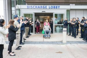 Everett police officers and civilian employees greet officer Chad House on Thursday, March 23, 2023, as he's wheeled out of Providence Regional Medical Center Everett. (Everett Police Department)