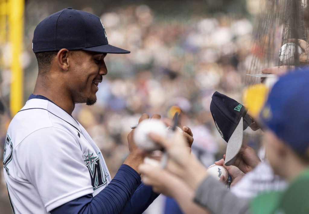 Mariners center fielder Julio Rodriguez signs autographs for fans before a game against the Royals on April 23, 2022, in Seattle. (AP Photo/Stephen Brashear)