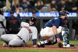 Cleveland Guardians' Mike Zunino slides home to score on a two-run single by Steven Kwan, as Seattle Mariners catcher Cal Raleigh waits for the throw during the fifth inning of a baseball game Friday, March 31, 2023, in Seattle. (AP Photo/Lindsey Wasson)