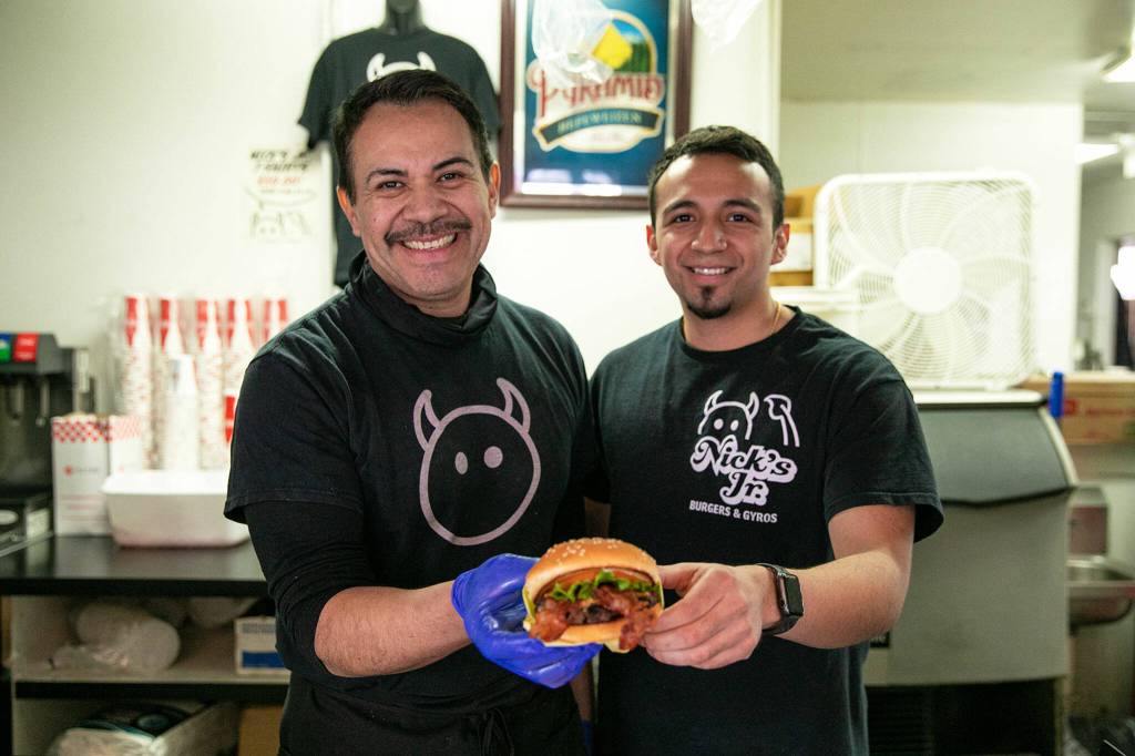 Owner Alfredo Rodriguez Sr. and his son Alfredo Jr. show off a peanut butter bacon burger on Friday, March 31, 2023, at Nicks Jr. in Everett, Washington. (Ryan Berry / The Herald)